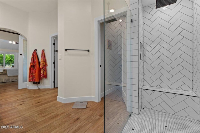 ensuite bathroom featuring baseboards, walk in shower, wood finished floors, and ensuite bath