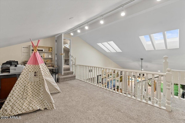 rec room with carpet flooring, rail lighting, and vaulted ceiling with skylight