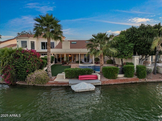 rear view of property featuring a water view and stucco siding