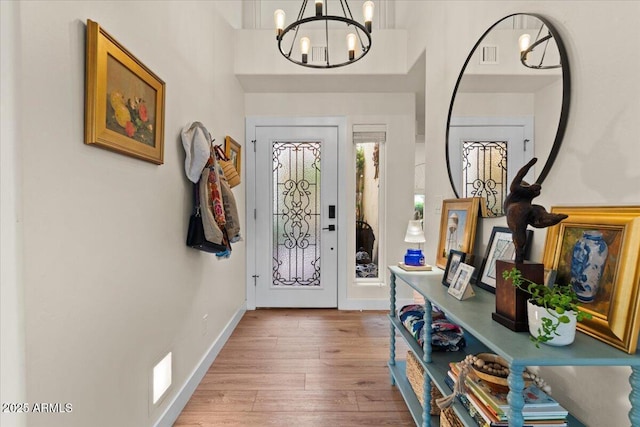 foyer entrance featuring an inviting chandelier, light wood-style flooring, baseboards, and visible vents