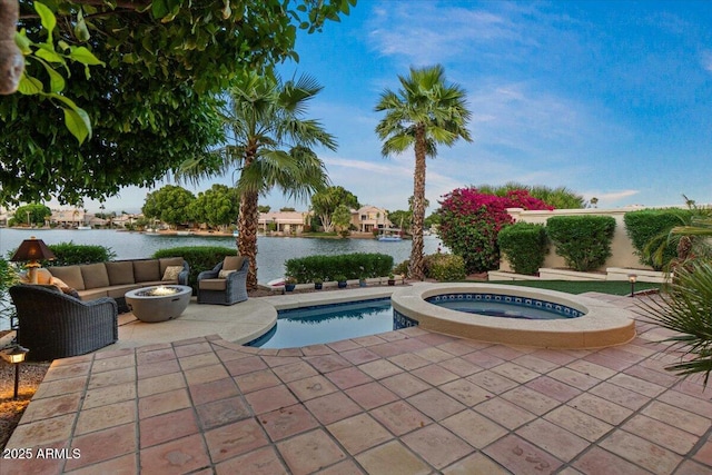 pool featuring a patio, an in ground hot tub, a water view, and an outdoor living space with a fire pit