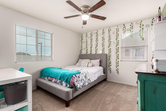 bedroom with light colored carpet, a ceiling fan, baseboards, and multiple windows