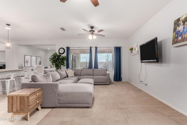 living area with visible vents, light tile patterned flooring, baseboards, light colored carpet, and ceiling fan