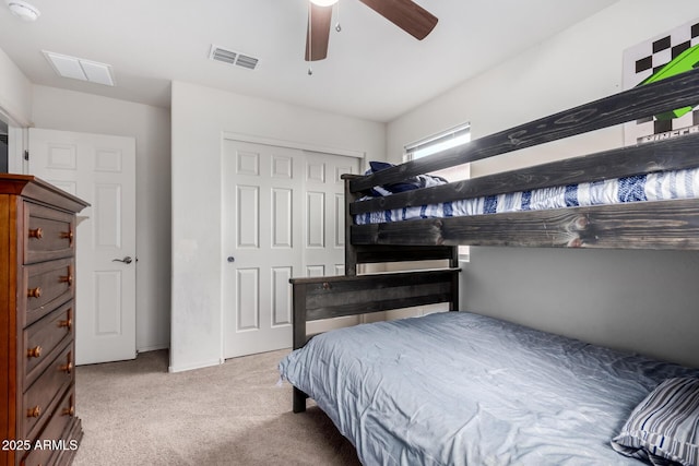 carpeted bedroom with visible vents, a closet, and a ceiling fan