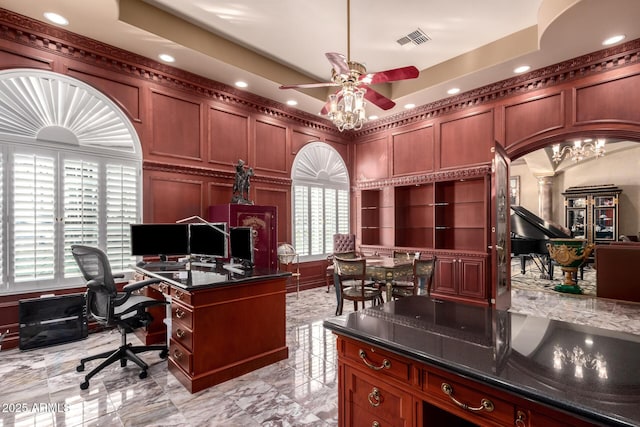 office with decorative columns, a raised ceiling, and ceiling fan