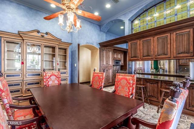 dining space featuring ceiling fan, ornamental molding, and a towering ceiling