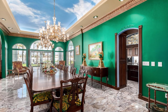 dining space with a raised ceiling, crown molding, and an inviting chandelier