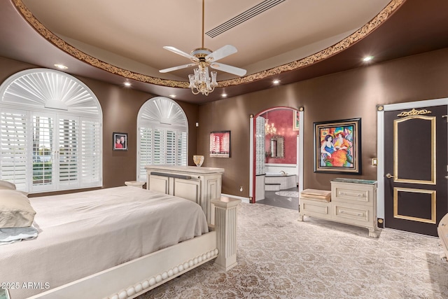 bedroom featuring connected bathroom, a tray ceiling, and light carpet