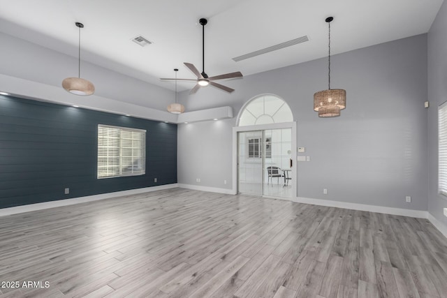 unfurnished living room featuring ceiling fan, a towering ceiling, and light wood-type flooring