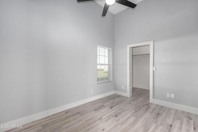 unfurnished room featuring a towering ceiling, light hardwood / wood-style flooring, and ceiling fan