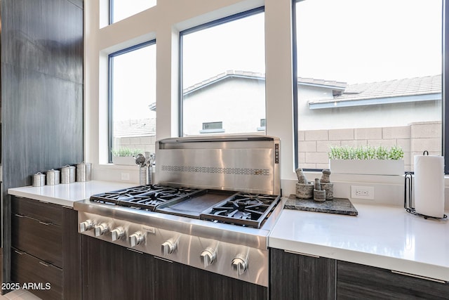 kitchen with decorative backsplash, dark brown cabinets, stove, modern cabinets, and light countertops