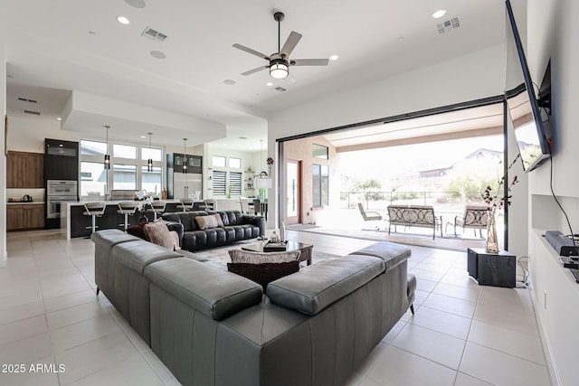 living area with light tile patterned floors, ceiling fan, and visible vents