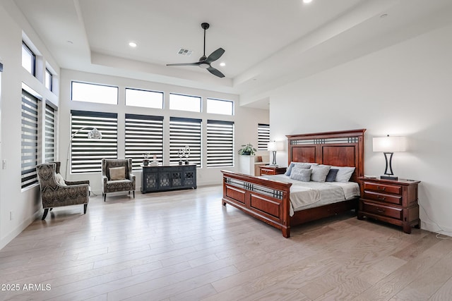 bedroom with ceiling fan, visible vents, light wood finished floors, a tray ceiling, and recessed lighting