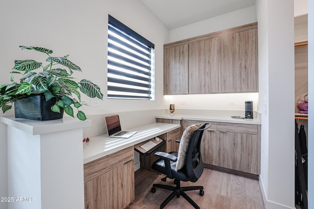 home office with built in study area and light wood finished floors