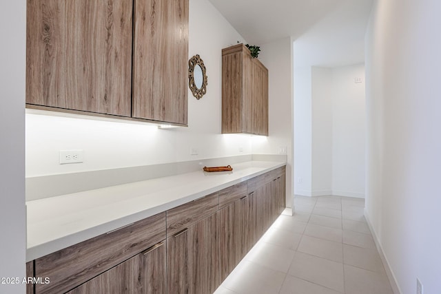interior space with modern cabinets, light tile patterned floors, light countertops, baseboards, and light brown cabinets