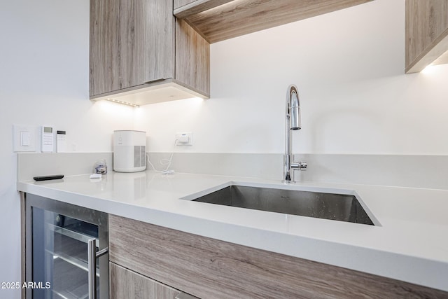kitchen featuring wine cooler, light brown cabinets, modern cabinets, light countertops, and a sink