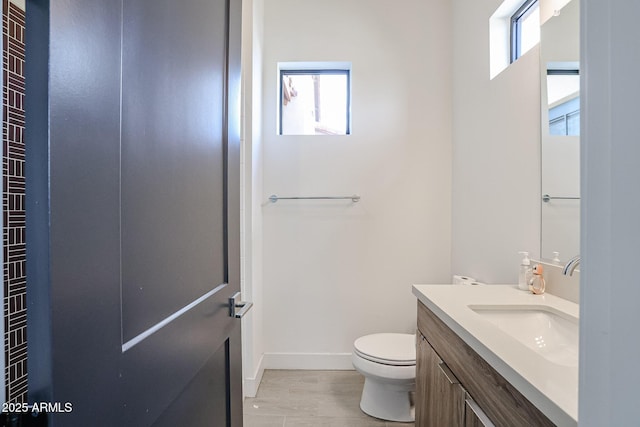bathroom with toilet, baseboards, and vanity