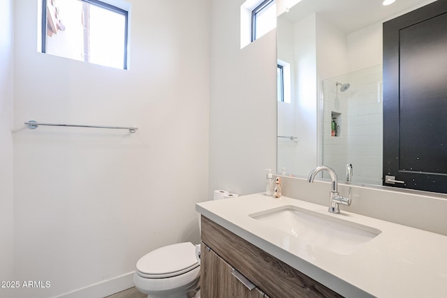 bathroom featuring vanity, toilet, and tiled shower