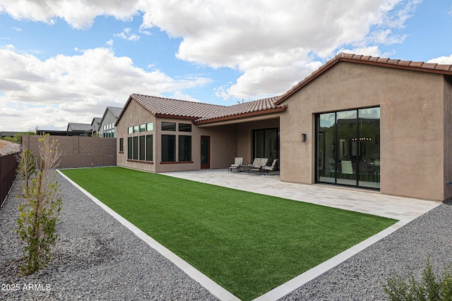 back of property with a tiled roof, a lawn, a fenced backyard, a patio, and stucco siding