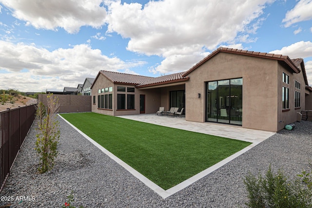 back of house featuring a lawn, a fenced backyard, stucco siding, and a tiled roof