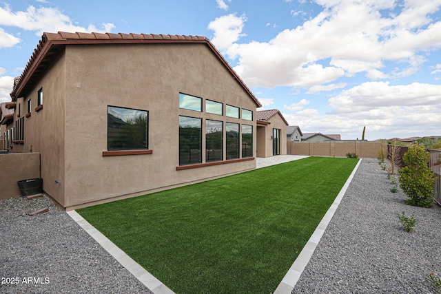 rear view of house with a fenced backyard and stucco siding