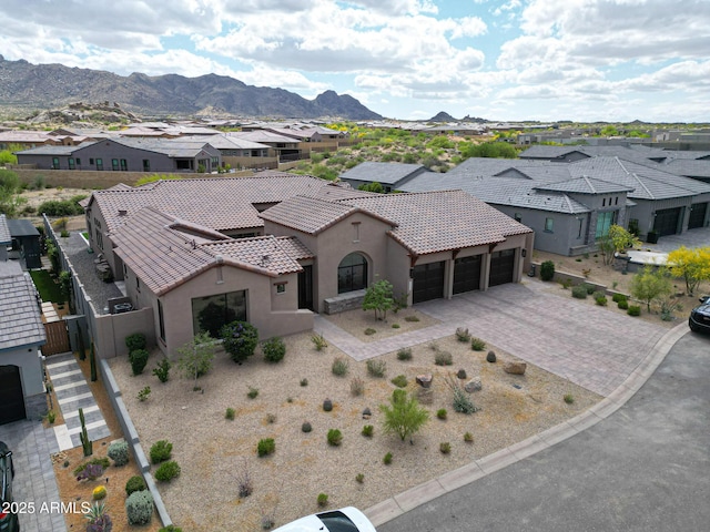 view of front facade featuring a residential view, an attached garage, a tile roof, stucco siding, and decorative driveway