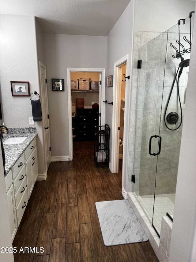 10704 E Twister Ave, Mesa, AZ 85212 - bathroom featuring a walk in closet, wood finished floors, a shower stall, vanity, and baseboards