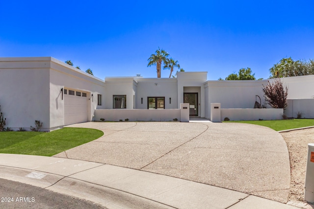 pueblo-style house with a garage and a front yard