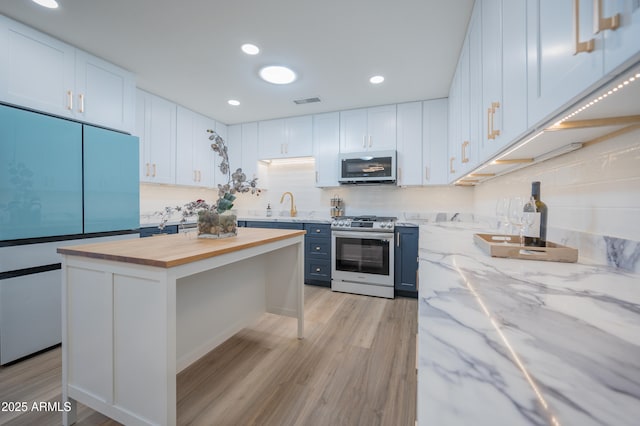 kitchen featuring white cabinetry, stainless steel range, a center island, and butcher block countertops