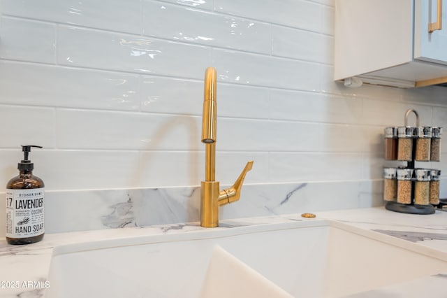 details featuring backsplash, white cabinets, and light stone counters