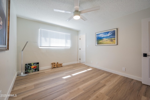 empty room with ceiling fan, light hardwood / wood-style flooring, and a textured ceiling