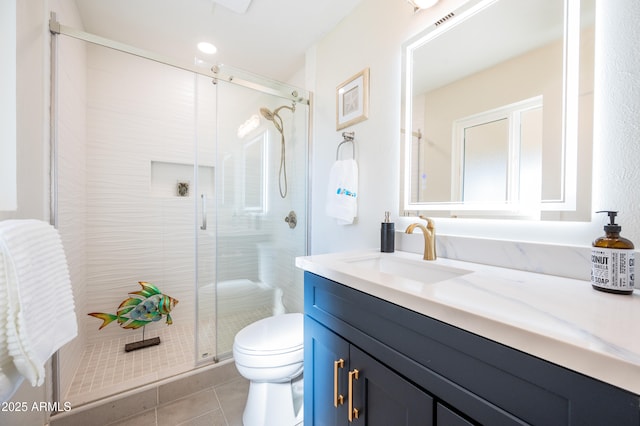 bathroom with tile patterned flooring, vanity, a shower with shower door, and toilet