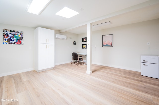 basement featuring an AC wall unit and light hardwood / wood-style flooring