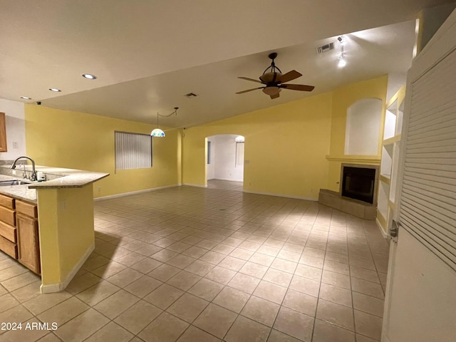 kitchen featuring ceiling fan, sink, light tile patterned floors, a fireplace, and lofted ceiling