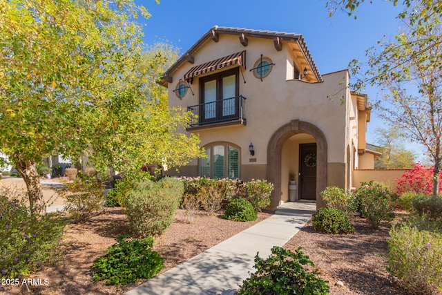 mediterranean / spanish home with a tiled roof, a balcony, and stucco siding