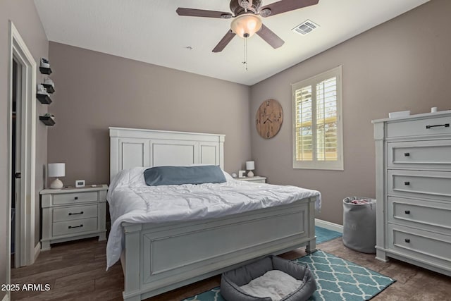 bedroom with dark wood-type flooring, a ceiling fan, visible vents, and baseboards