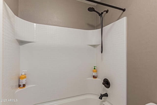 bathroom featuring washtub / shower combination and a textured wall