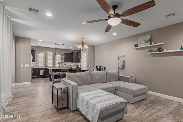 living room with light wood-type flooring, baseboards, and visible vents