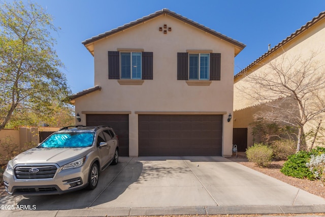 view of front of property featuring a garage, driveway, a tiled roof, and stucco siding