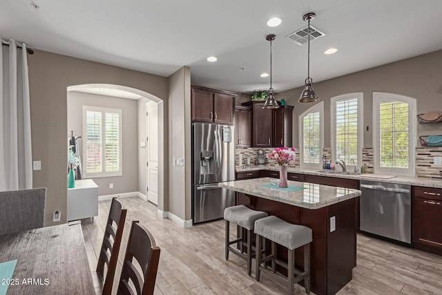 kitchen with appliances with stainless steel finishes, visible vents, plenty of natural light, and backsplash