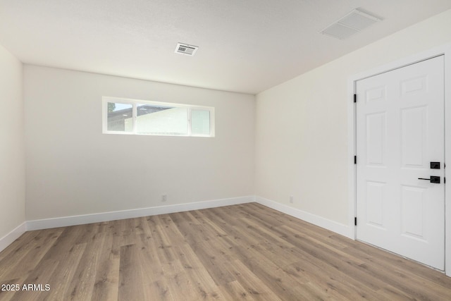 spare room featuring baseboards, visible vents, and light wood-style floors