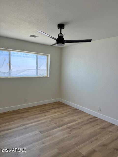 spare room with baseboards, ceiling fan, light wood finished floors, and visible vents