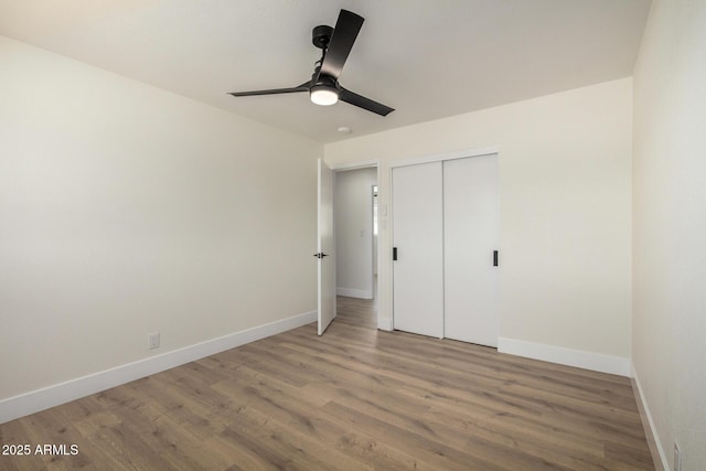 unfurnished bedroom featuring light wood-style floors, baseboards, ceiling fan, and a closet