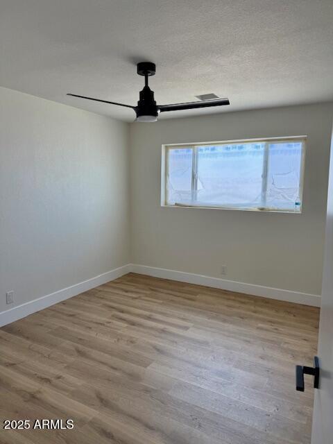 spare room featuring baseboards, a ceiling fan, and wood finished floors