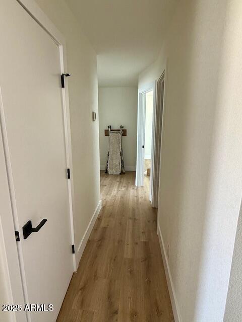 corridor with baseboards and light wood-style floors