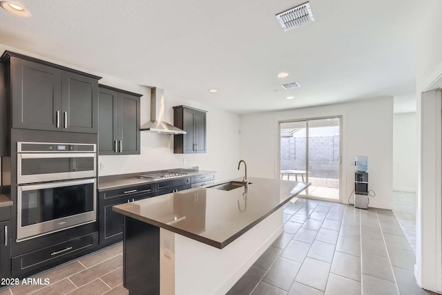 2364 N 212th Ave, Buckeye, AZ 85396 - kitchen with a sink, wall chimney exhaust hood, stainless steel appliances, a kitchen island with sink, and light tile patterned floors