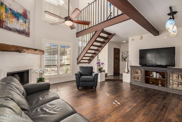 living room with ceiling fan, beamed ceiling, and wood-type flooring