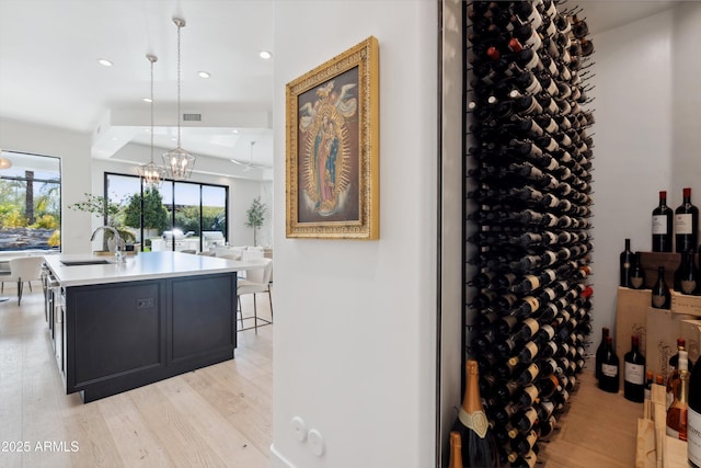 wine cellar featuring sink, a chandelier, and light hardwood / wood-style floors