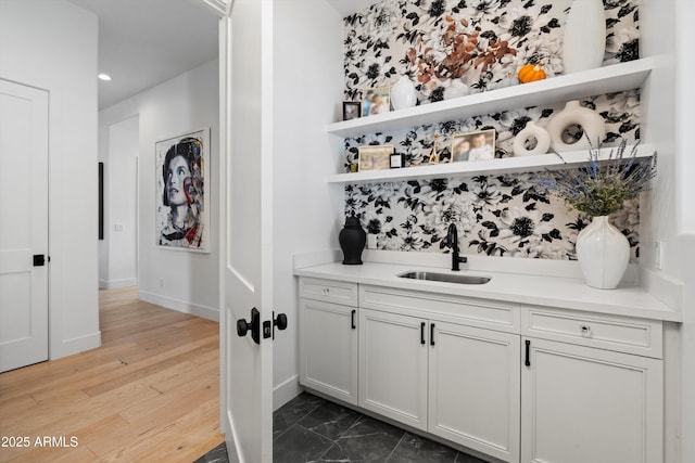 bar featuring white cabinetry, sink, and hardwood / wood-style floors