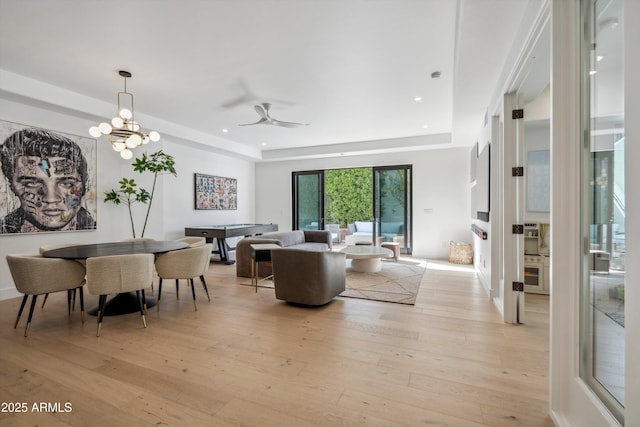 living room featuring a raised ceiling, a notable chandelier, and light hardwood / wood-style floors